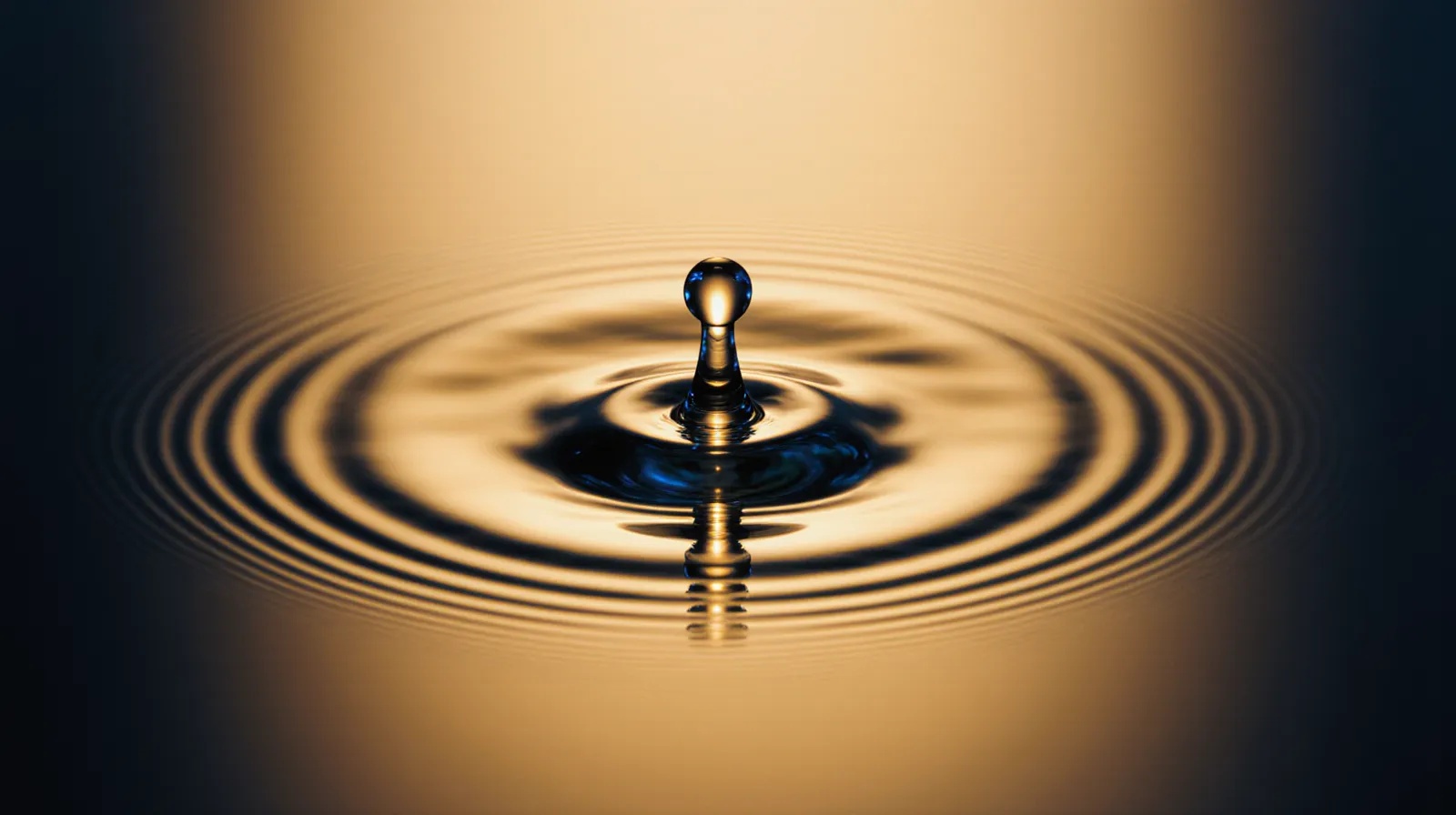 Close-up blood droplet with golden backlight on navy background